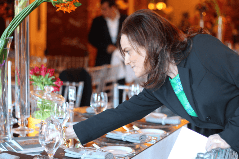 Penny apparecchia con cura un'elegante tavola con bicchieri, fiori e decorazioni per un'occasione speciale in Israele.