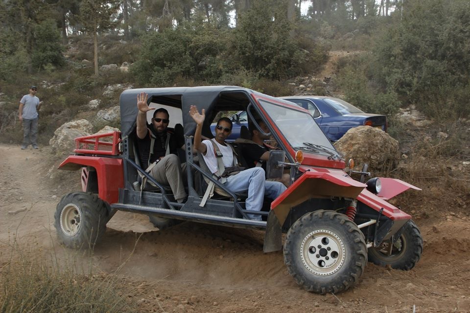חברי מצוק מנופפים מכרכרה אדומה על שביל עפר ביער