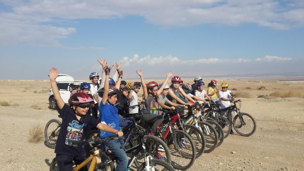 Matzok kids cycling group with hands up in the desert