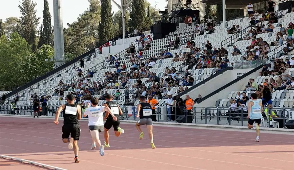 Runners competing on the track in front of spectators at Grand Slam Jerusalem